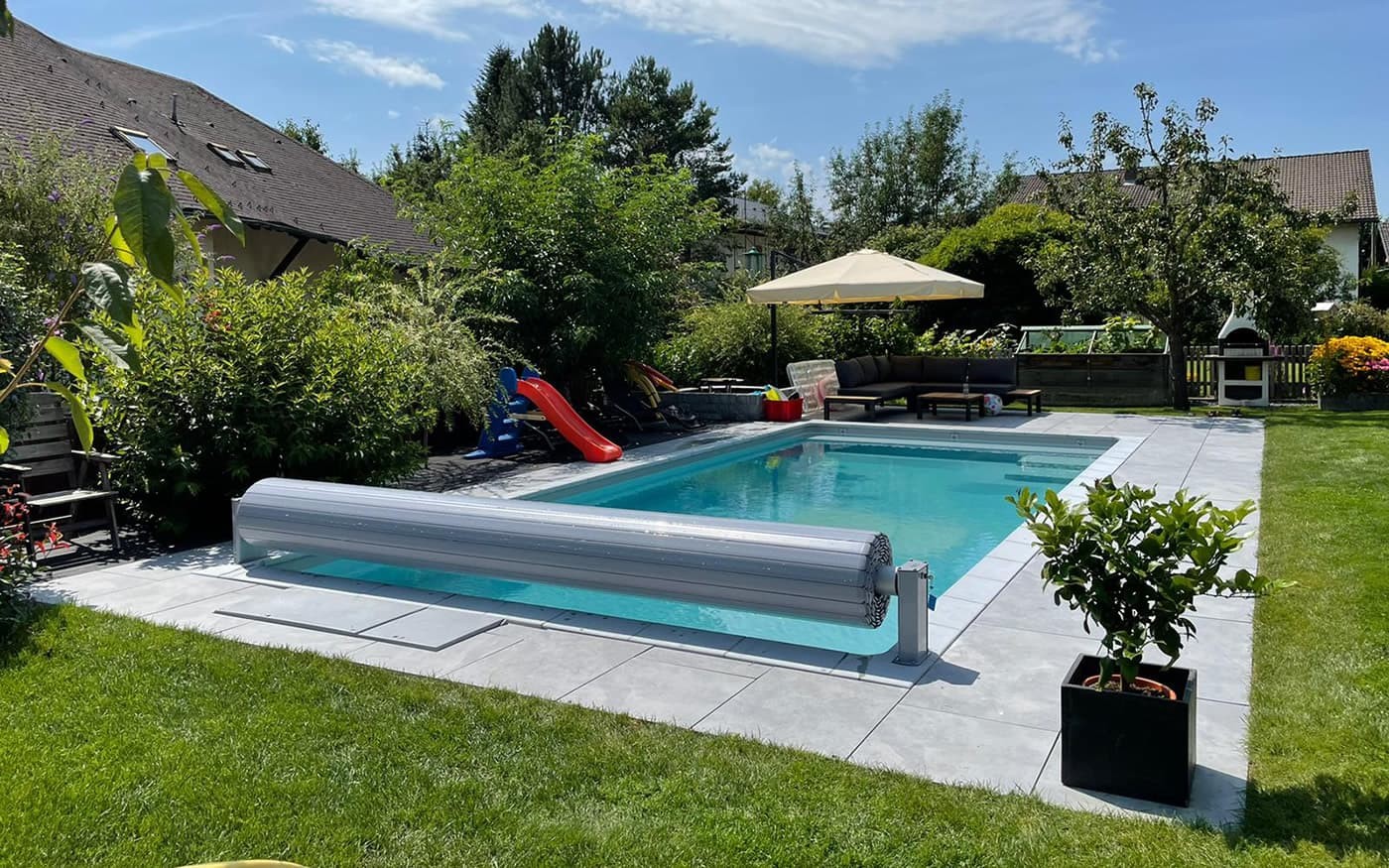 Pool vom Poolbau Gollner mit Liegestühlen und Sonnenschirm vor Bergkulisse